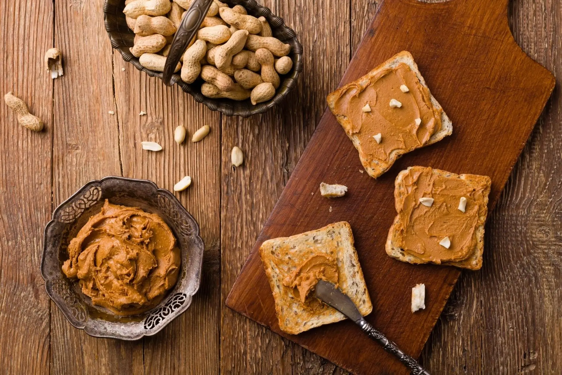 A wooden table topped with peanut butter and crackers.